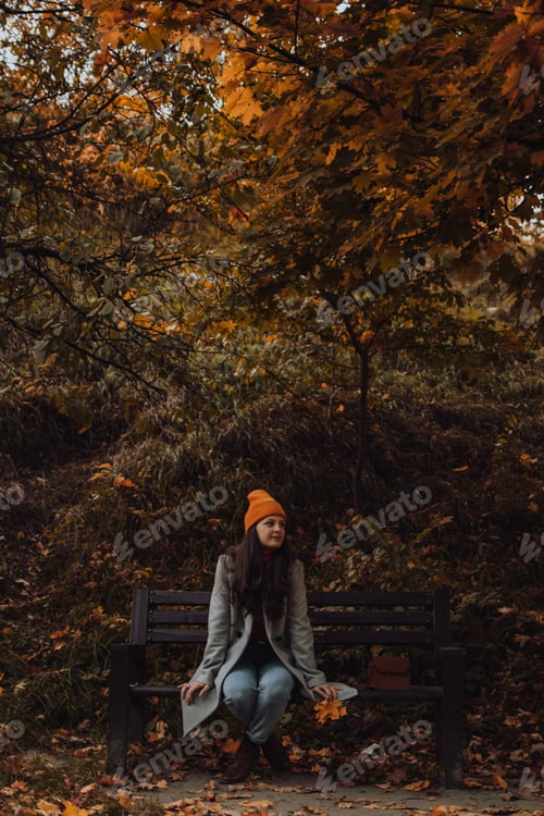 Preview: A young woman is sitting on a bench and looking somewhere