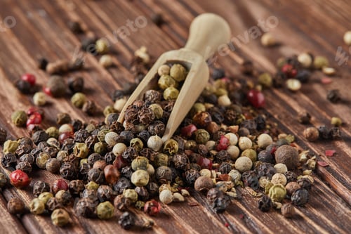 Preview: Multicolored pepper mix with wooden spatula scattered over vintage wooden background