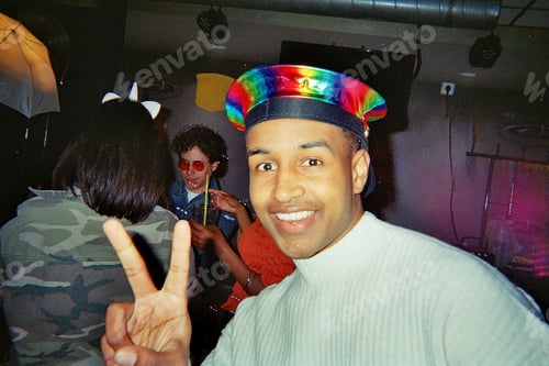 Preview: Smiling man making peace sign at retro party