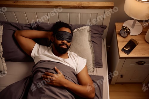 Preview: Above view of black man with eye mask sleeping at night.