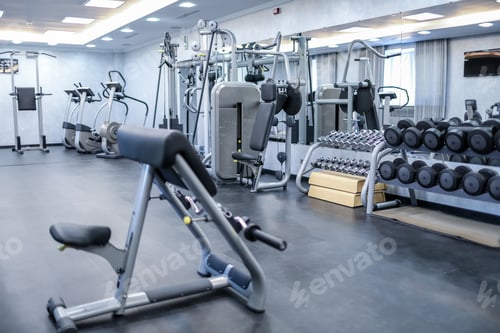 Preview: Empty gym with strength training machines, free weights, and cardio equipment in bright room.
