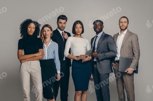 Preview: Confident young business people looking at camera while standing on beige background together