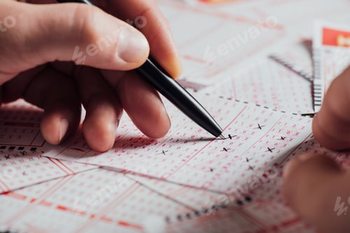 Preview: cropped view of gambler marking numbers in lottery tickets with pen