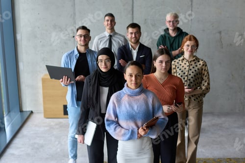 Preview: A diverse and determined team of business professionals stands confidently in an office, ready to