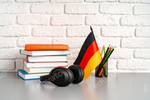 Preview: Stack of books and flag of Germany on desk. German language learning concept