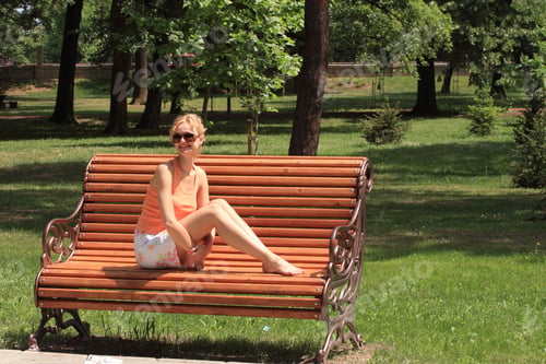 Preview: blonde lady relaxing on a park bench enjoying nature