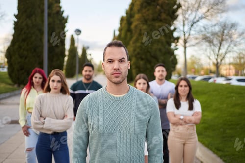 Preview: Man looking serious at the camera while standing in front of a group of people.