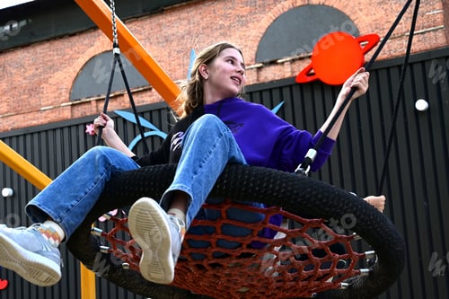 Preview: A girl swings on a round swing on the playground