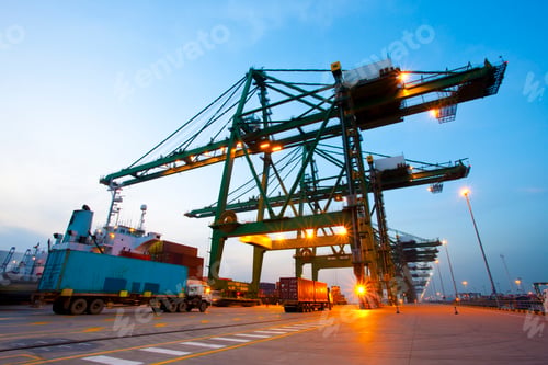 Preview: Cranes, cargo containers and trucks at a shipping port during dusk