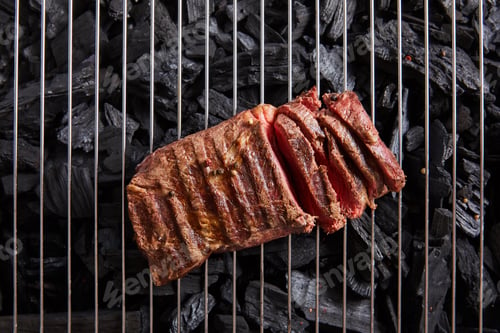 Preview: top view of cut fresh grilled tasty steak with rare roasting on grate above black coals