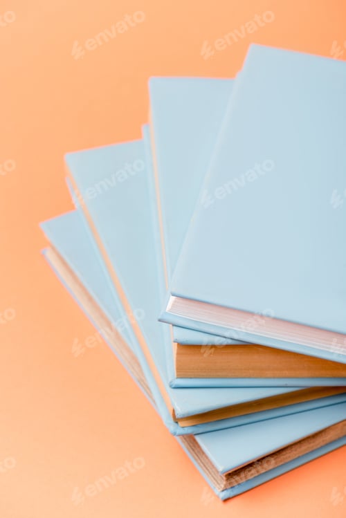 Preview: selective focus of stack of blue books on orange surface