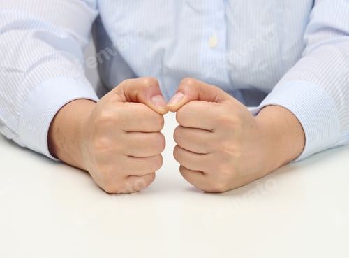 Preview: Two female hands folded into a fist on a white table. Strict leader