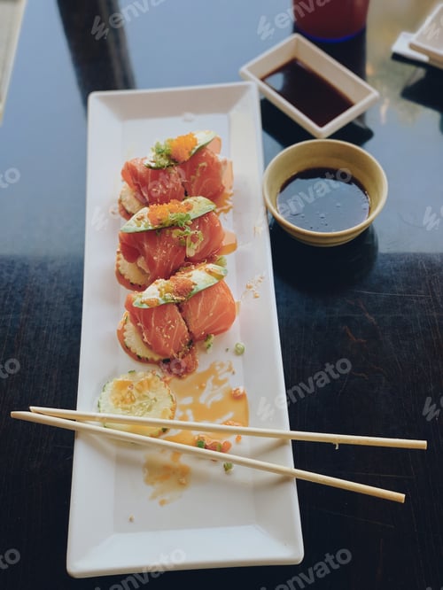 Visualização: Rolo de sushi de salmão cortado em uma mesa preta à luz de uma janela