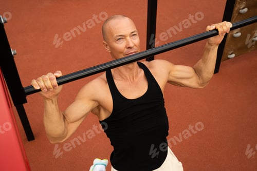 Preview: Athlete muscular fitness male pulling up on horizontal bar at street gym. Outdoors.