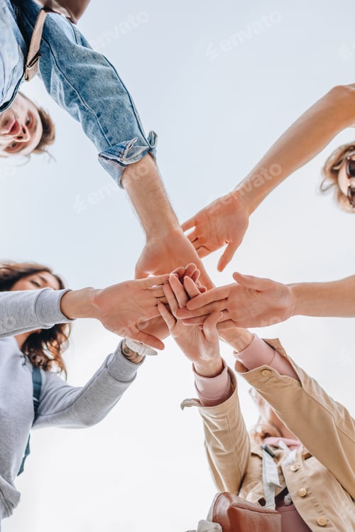 Vista previa: vista inferior de jóvenes amigos juntando las manos