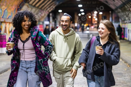 Preview: Diverse friends laughing walking in urban tunnel at night