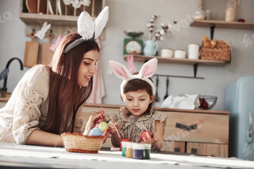 Preview: Mother and daughter in bunny ears at easter time have some fun in the kitchen at daytime