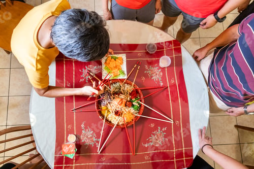 Preview: Person placing raw salmon belly onto a serving of yusheng or yee sang during Chinese New Year