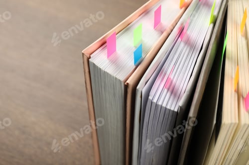 Preview: Books with colorful tabs on brown table, closeup. Space for text