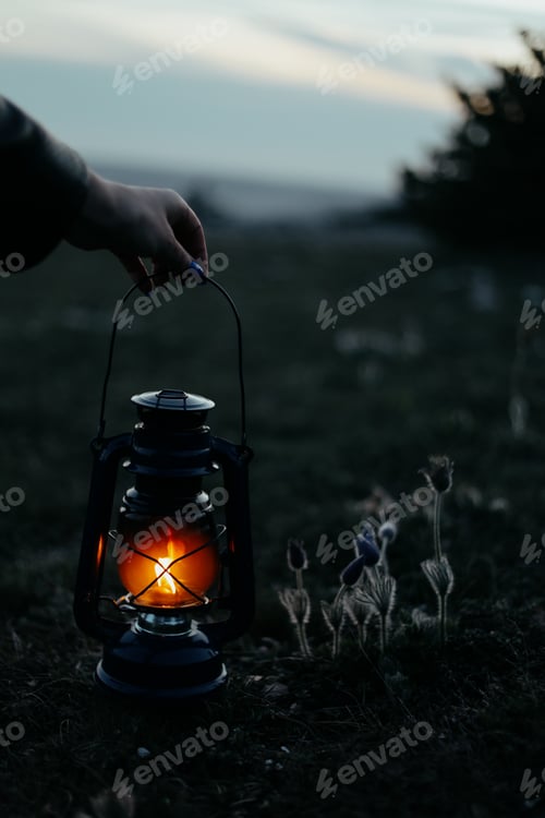 Preview: female hands holding a burning kerosene lamp