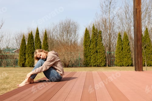 Preview: A young woman sits on a terrace in the yard early spring