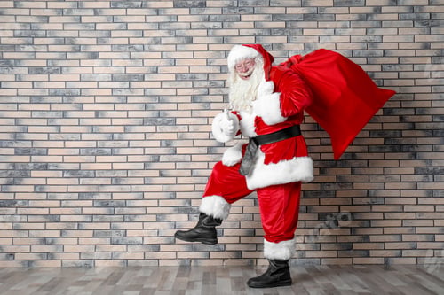 Preview: Authentic Santa Claus with big red bag full of gifts near brick wall