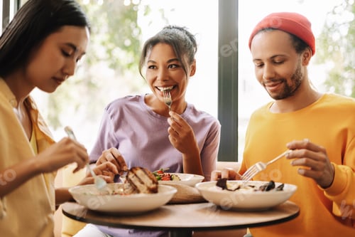 Preview: Happy diverse multiracial friends enjoying meal together in restaurant