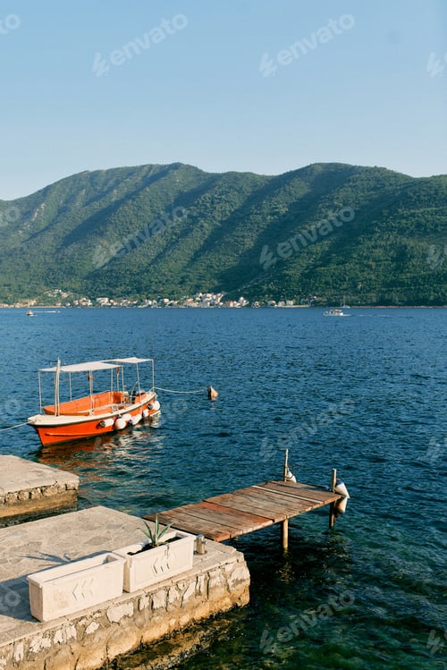 Preview: Red excursion boat moored at the pier against the backdrop of mountains