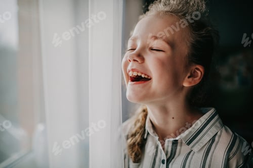 Preview: Portrait of a cheerful laughing girl at the window