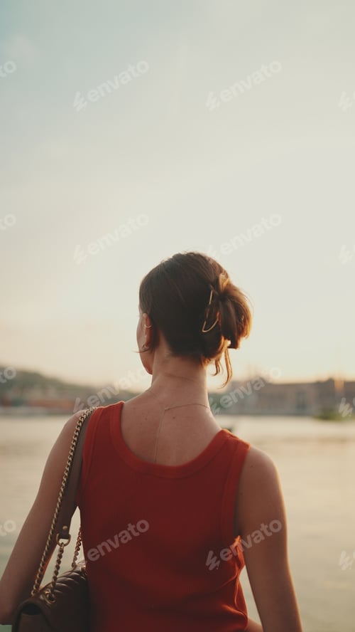 Preview: Young woman looks at the sea in the morning time. Back view