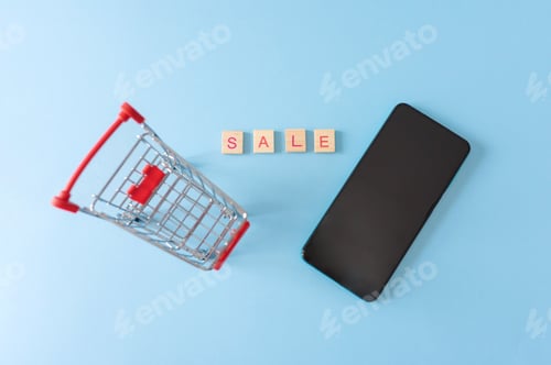 Preview: top view of Small shopping cart with smartphone and word sale on blue background