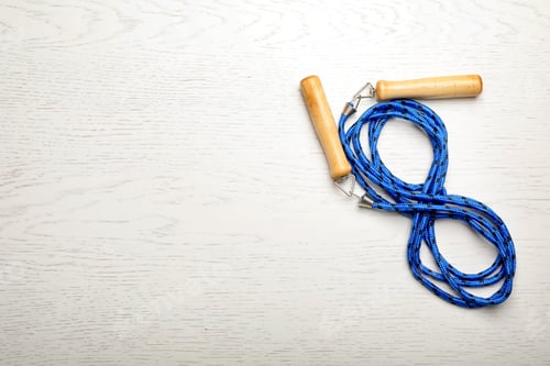 Preview: Jump rope and space for text on white wooden background, top view