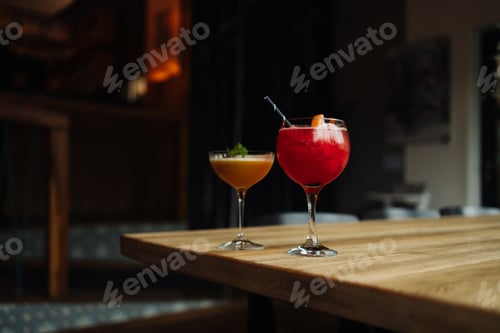 Preview: Two colorful summer cocktails in glasses on wooden table. Assortment of fresh summer drinks. Red