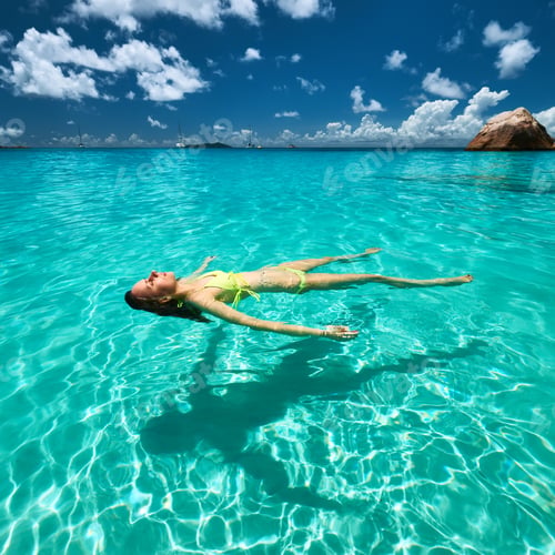 Preview: Woman In Yellow Bikini Lying On Water At Tropical Beach