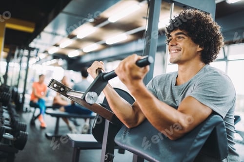 Preview: Young handsome man doing exercises in gym