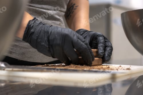 Preview: chef cutting sweet chocolate bars with caramel filling , fudge candy for cheesecake preparation
