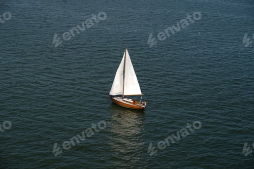 Preview: Aerial view of wooden old yacht with sail against backdrop of blue water with waves and ripples.