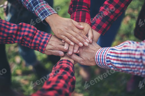 Preview: Close up top view of young business people putting their hands together. Unity and teamwork concept.