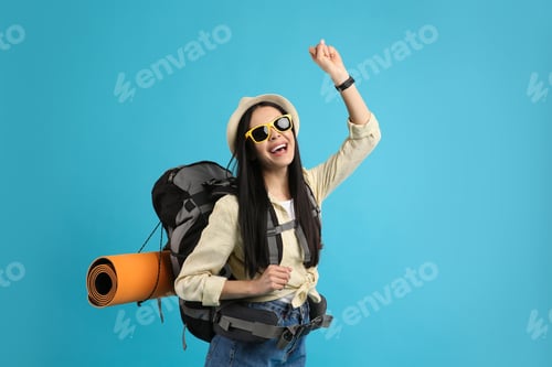 Preview: Happy female tourist with backpack on light blue background