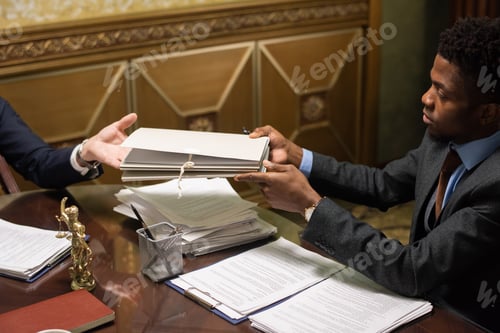 Preview: Young male lawyer passing folder with papers to colleague