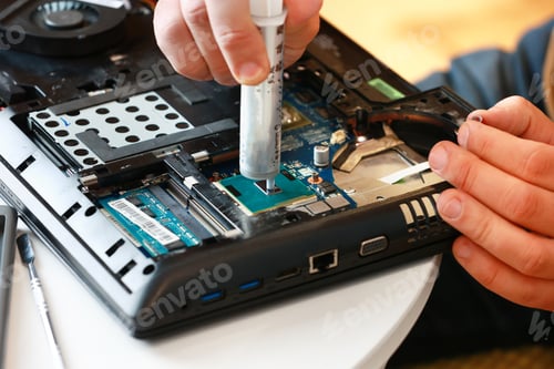 Preview: Hand a repairman uses thermal paste syringe apply thermal compound to a CPU. Master replaces thermal