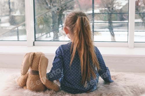 Preview: Lonely little girl with toy sitting near window indoors. Autism concept