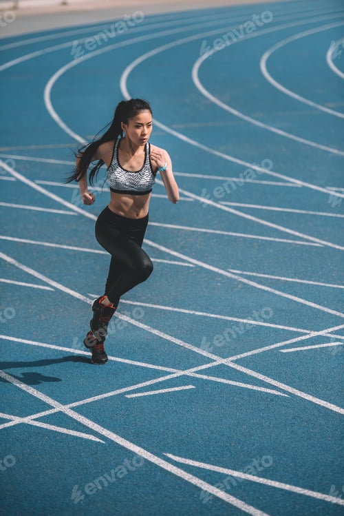 Preview: Athletic young sportswoman sprinting on running track stadium