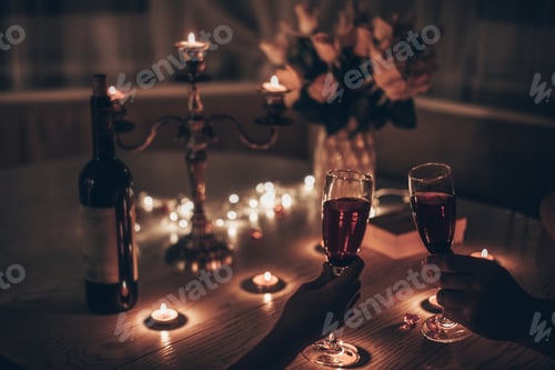 Preview: Couple with glasses of wine having romantic candlelight dinner at table at home,