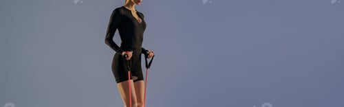 Preview: Side view of woman performs fitness exercises with resistance band on studio background