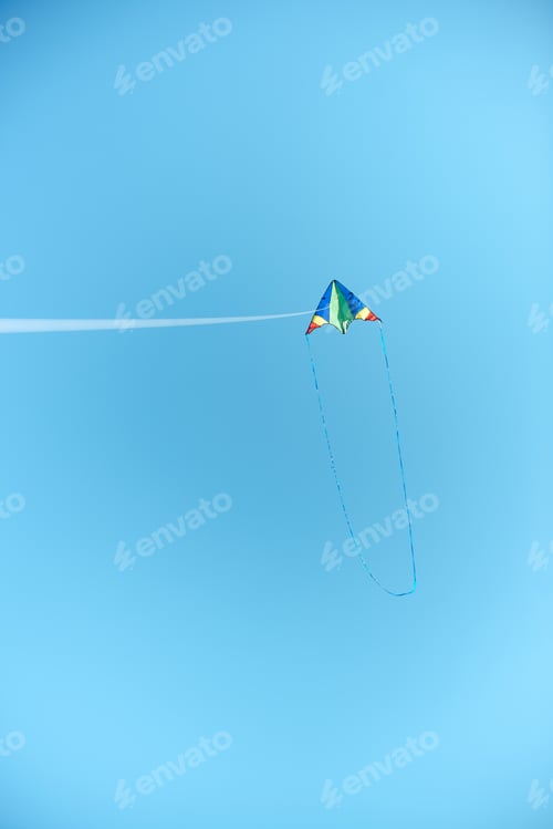 Preview: colorful kite flying high in blue clear sky