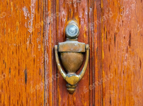 Preview: Close-up of a folding knocker on the background of a weathered wooden door. Vintage decor.