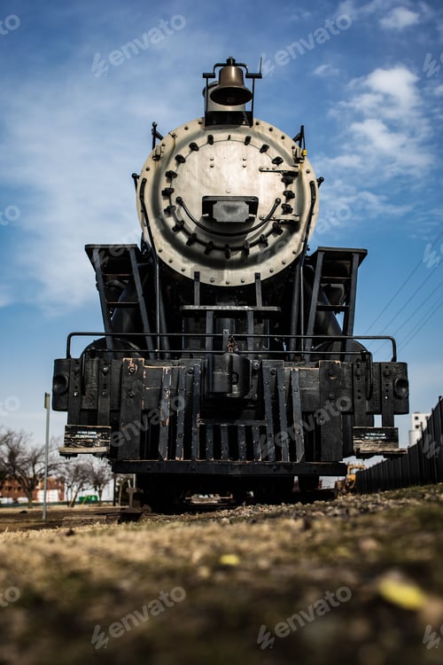 Preview: Low-angle vertical shot of an old black train parked on a railroad