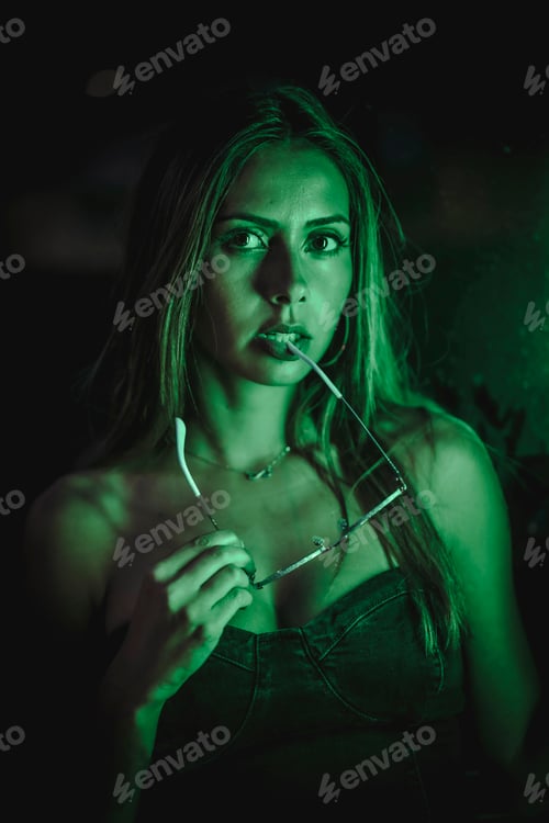 Preview: Caucasian brunette in a black dress illuminated by green led light reflected