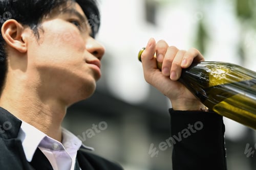 Preview: Asian man alcoholic drinking beer from bottle outdoors. Alcohol addiction and unemployed concept